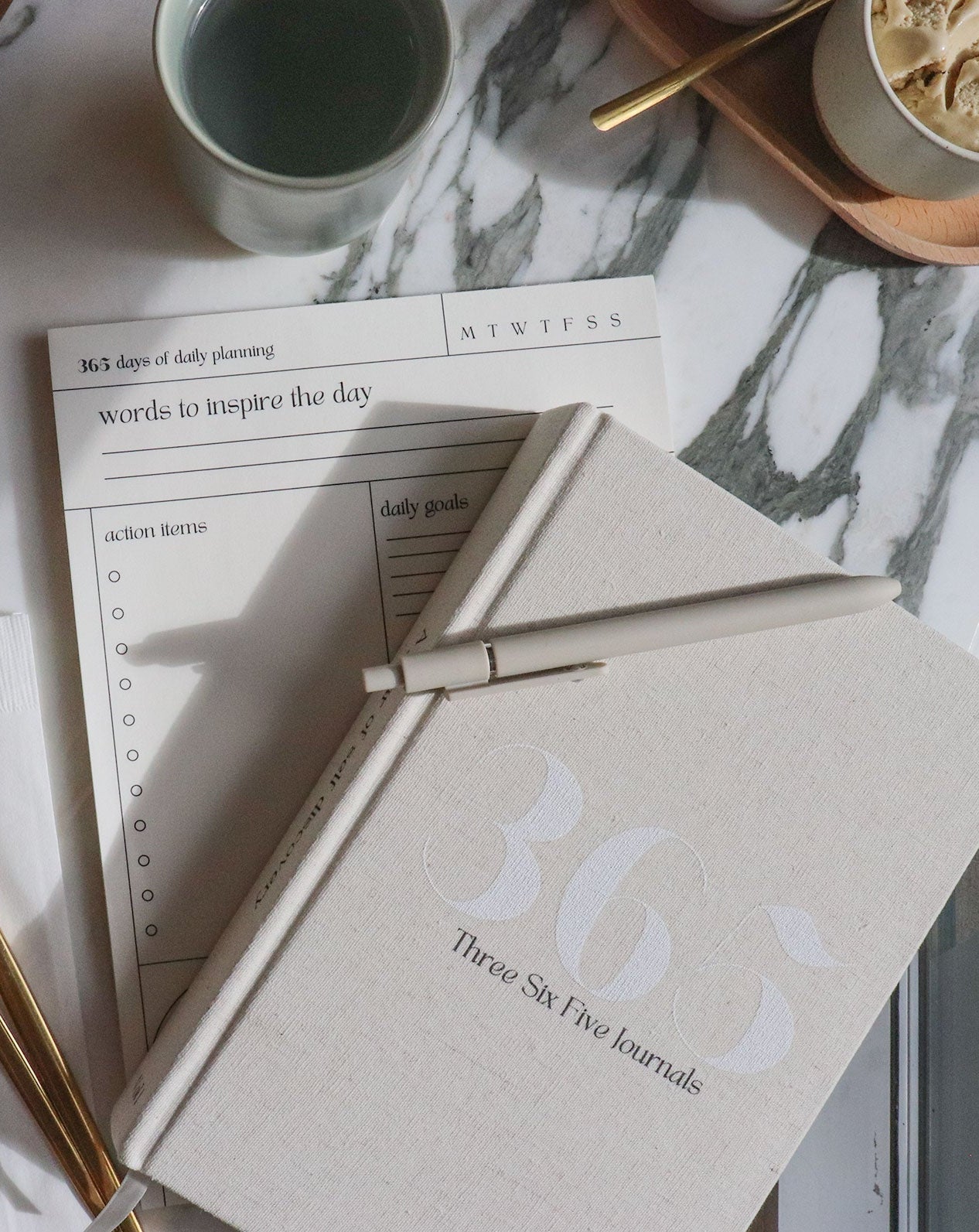 365 Journal with pen, daily align notepad, and mug on a marble surface