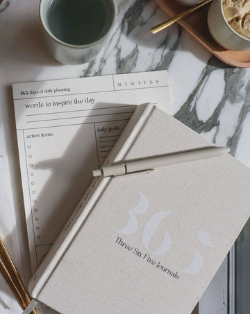 365 Journal with pen, daily align notepad, and mug on a marble surface