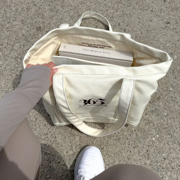 White tote bag with '365' logo on a concrete surface