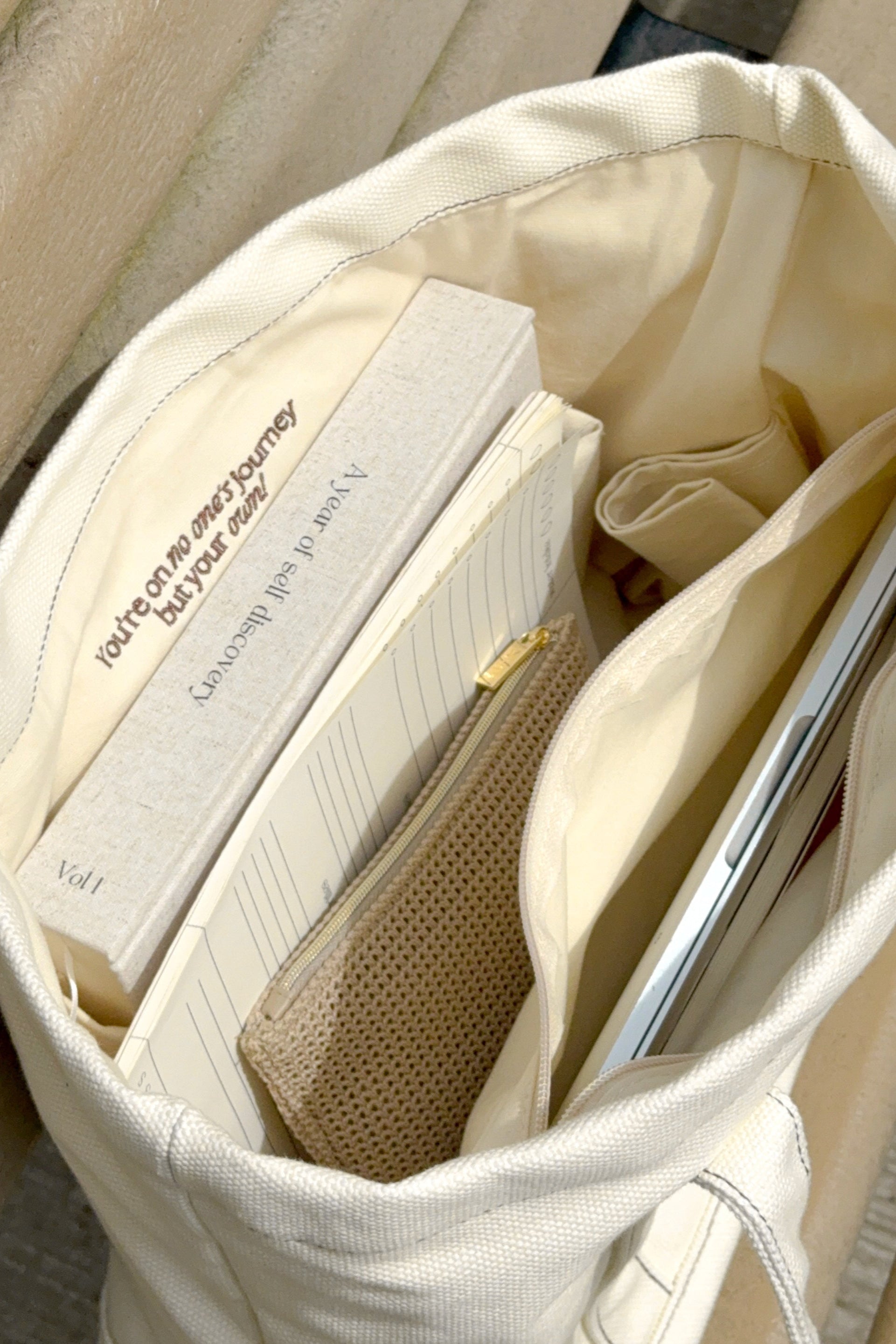 Open beige bag with books and a pen inside