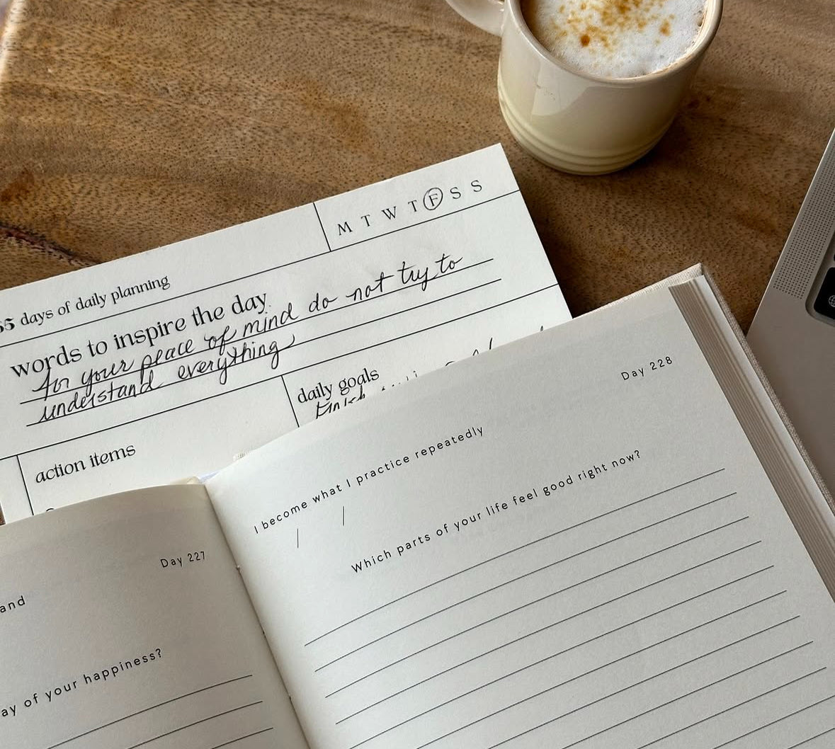 open journal book on top of Daily Align notepad with coffee on wood surface
